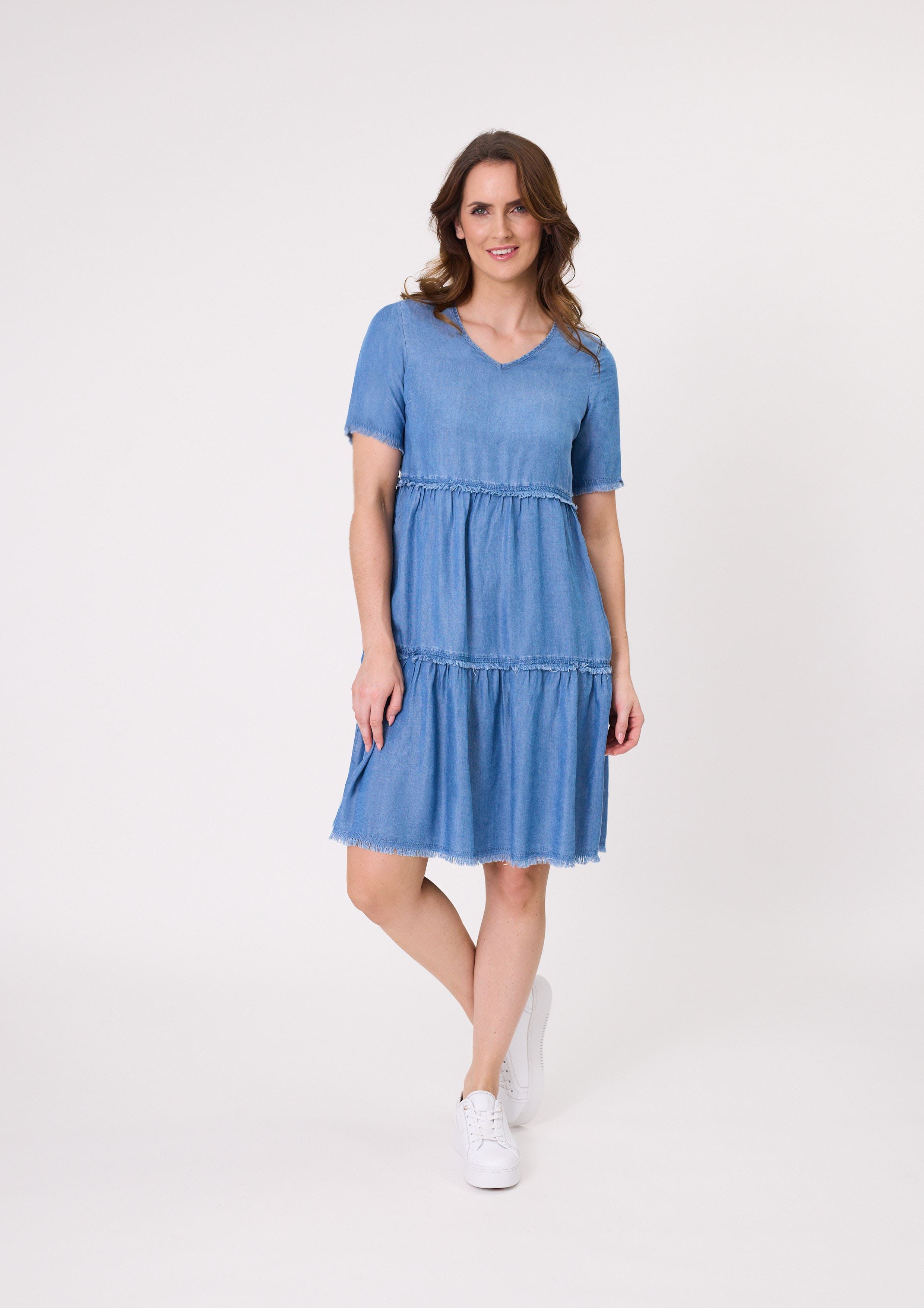 Beatrice Dress in soft chambray with a denim-like look, featuring frayed edges, a tiered skirt, and knee-length design, made from a breathable cotton-viscose blend.