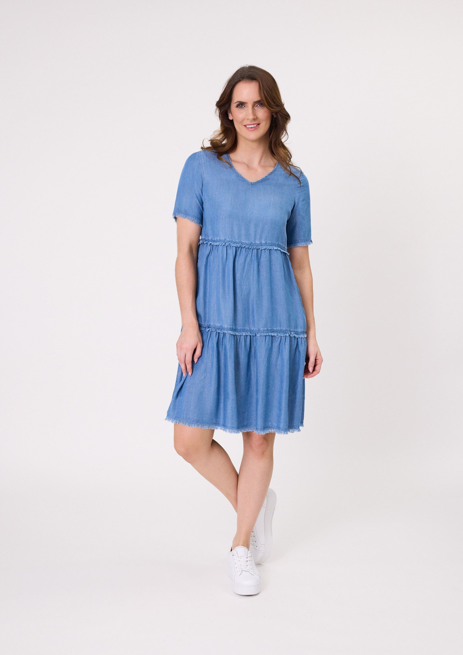 Beatrice Dress in soft chambray with a denim-like look, featuring frayed edges, a tiered skirt, and knee-length design, made from a breathable cotton-viscose blend.