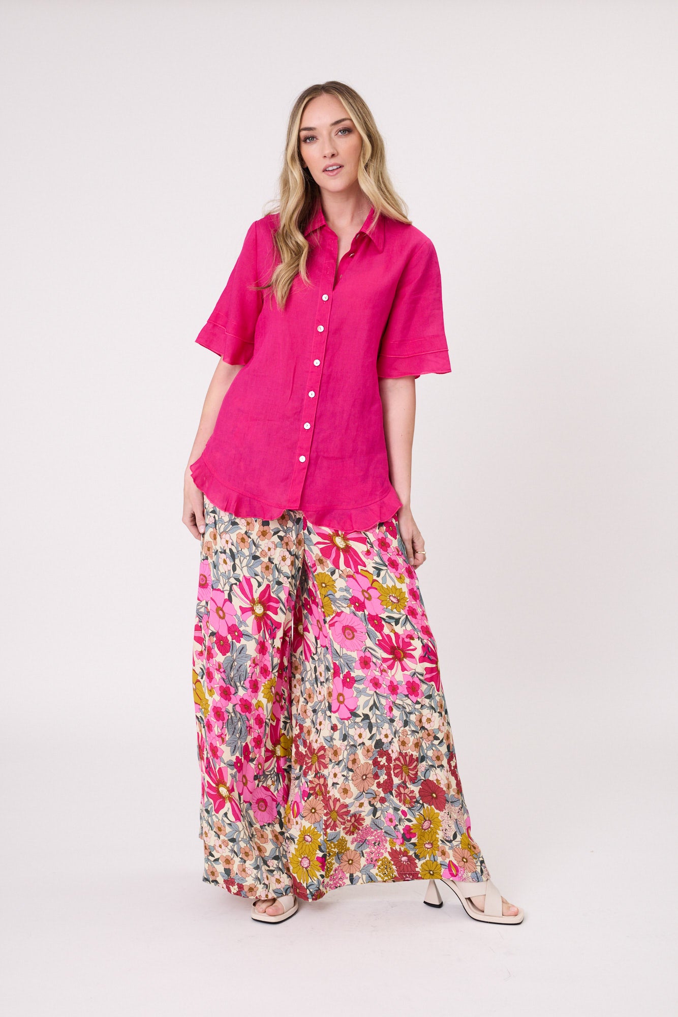 Camilla Linen Top in fuchsia with a classic collar, button-up front, and short sleeves featuring delicate frill detailing on the sleeves and hem.