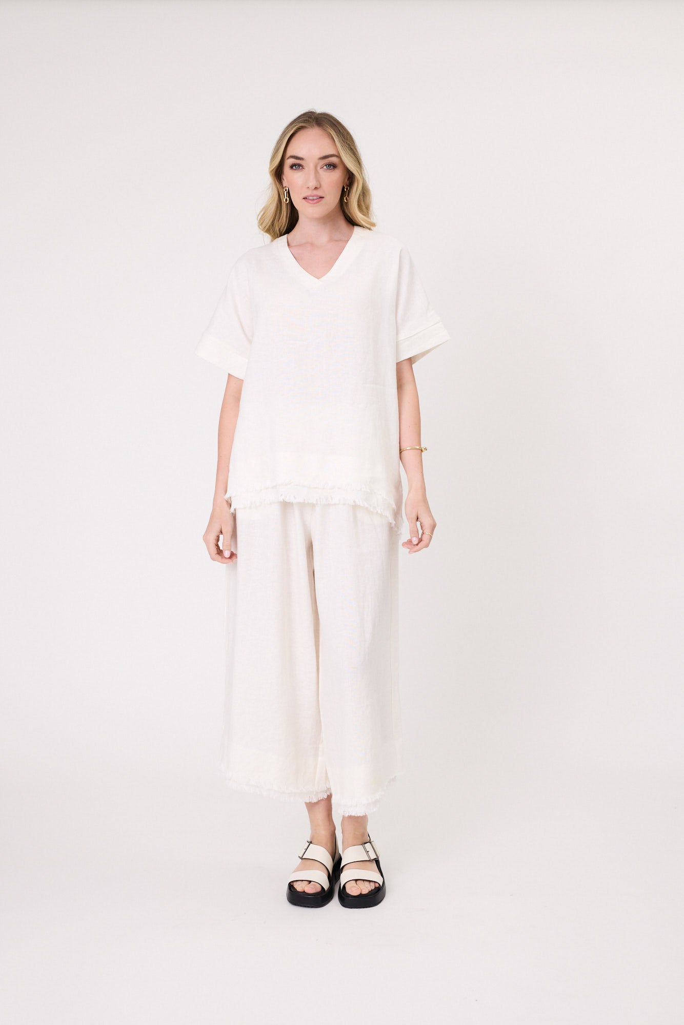 Carola Linen Top in white with a relaxed fit, V-neckline, short sleeves, and frayed hem, made from breathable linen for warm-weather comfort.