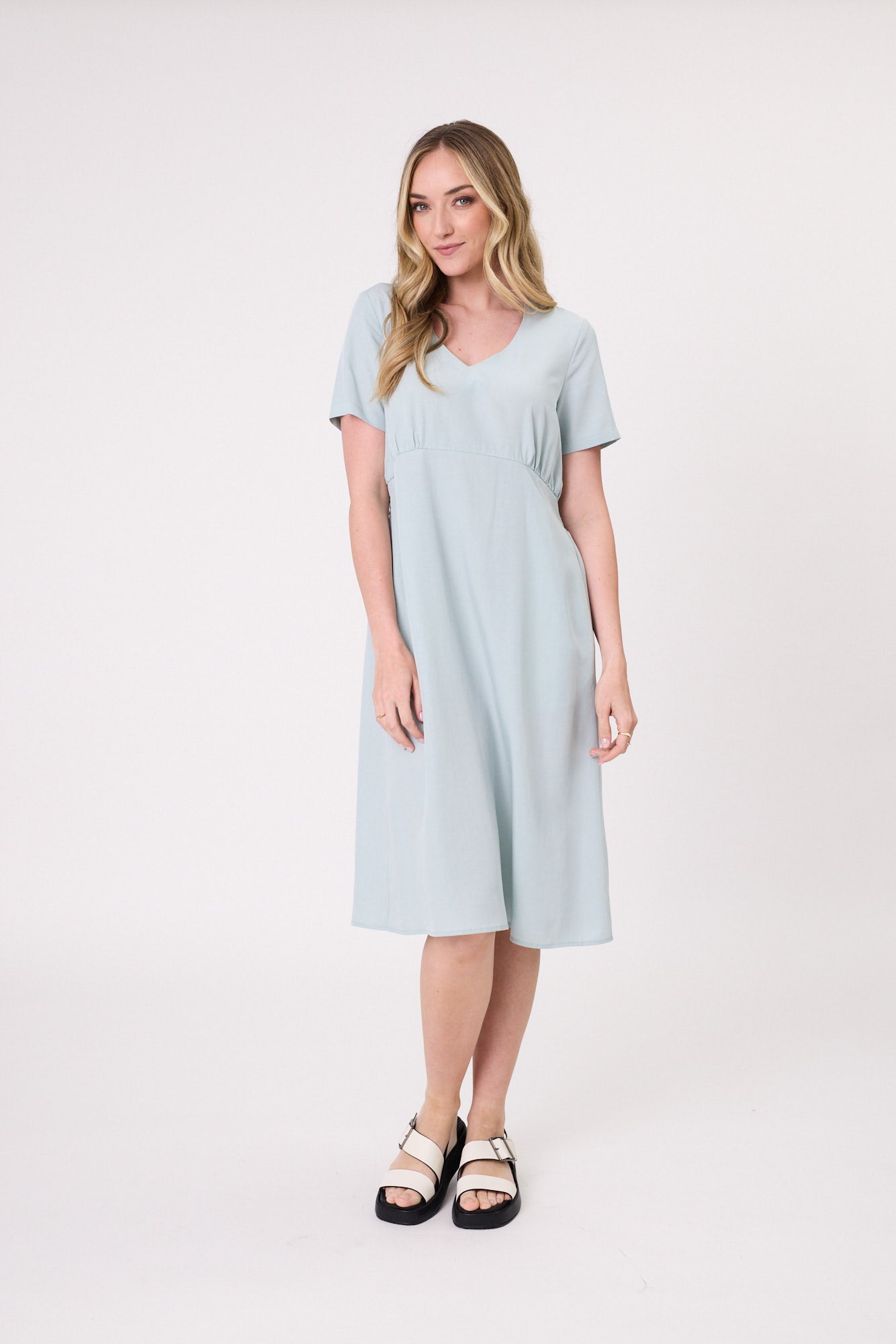 Emilia Dress in aqua with a V-neckline, short sleeves, gentle gathers under the bust, and a knee-length silhouette, made from a soft, breathable Tencel-linen blend.