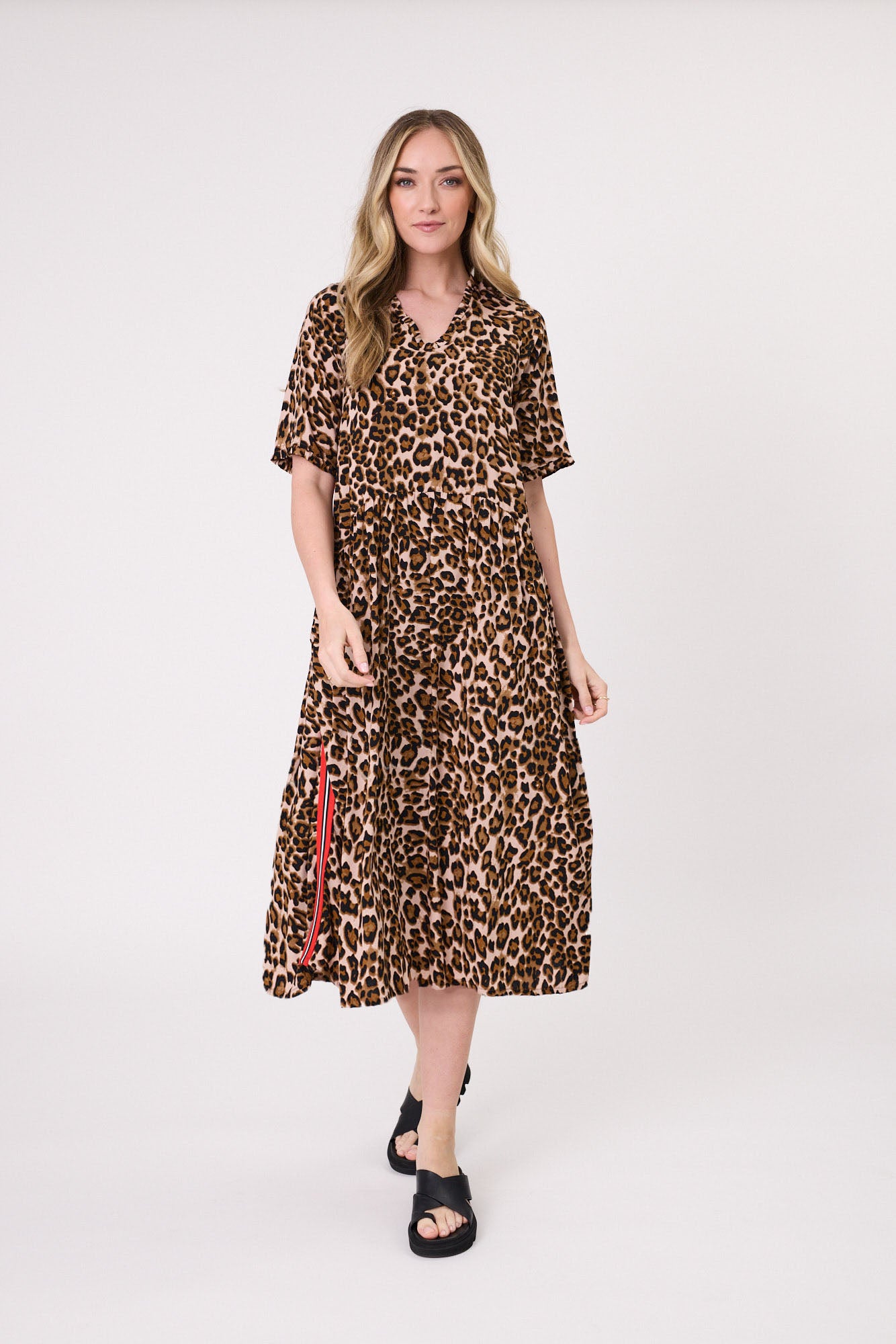 Leona Dress in leopard print with bold red, white, and black side stripes, V-neckline, short sleeves, and side pockets. Knee-length for an easy everyday look.
