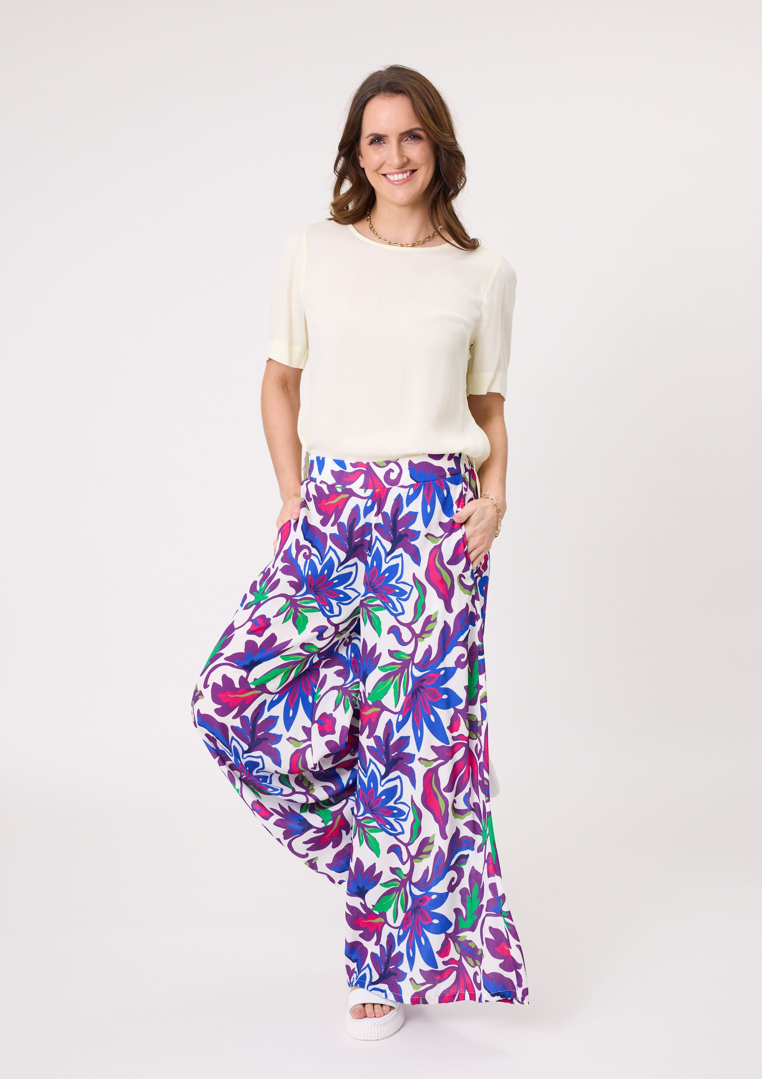 Massima Pant with bold floral print in blue, green, purple, and cerise, featuring a wide-leg silhouette, flowy drape, and practical pockets, made from a soft rayon-viscose blend.