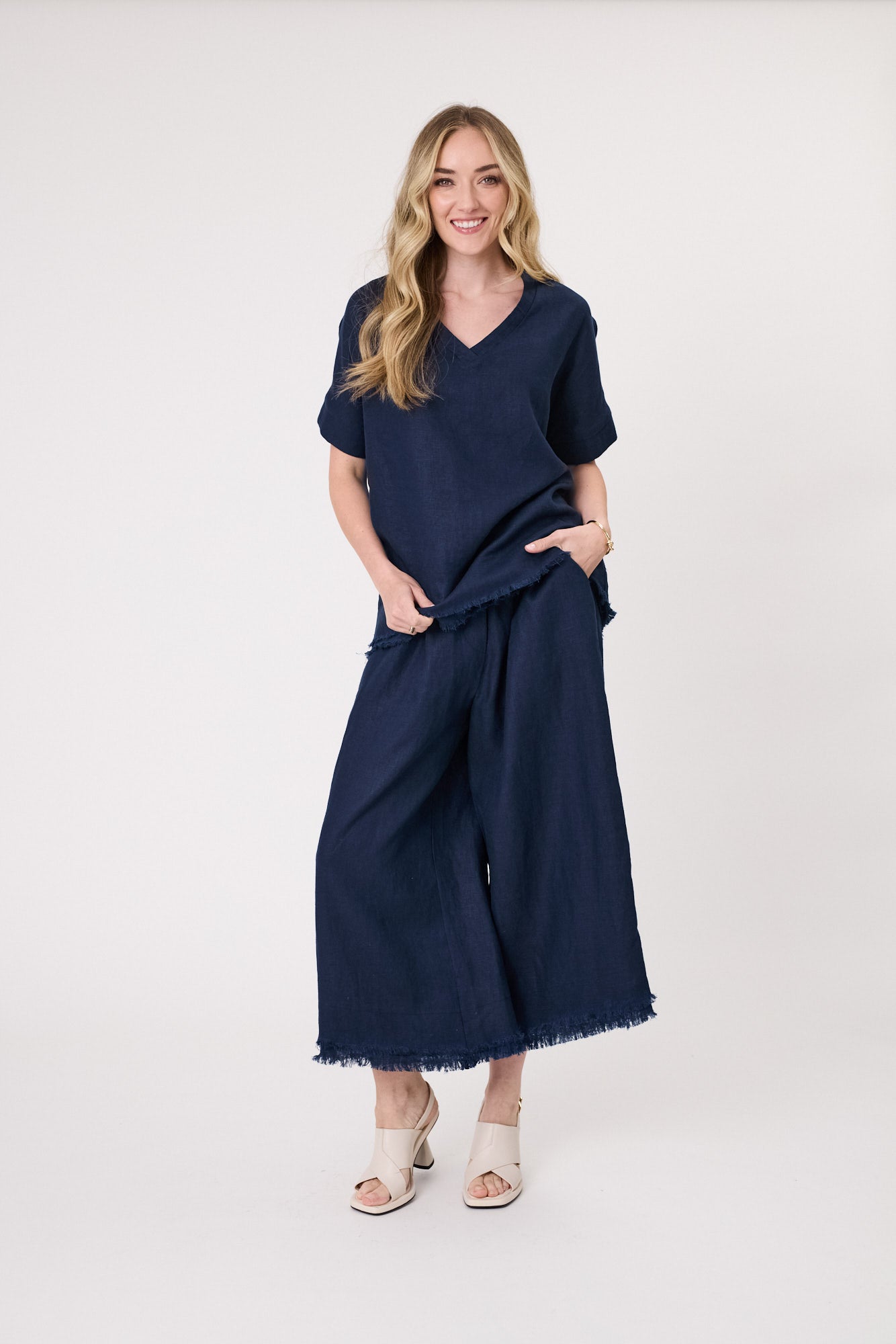 Nicole Linen Pant in navy with a loose fit, side pockets, frayed hem, and three-quarter length.