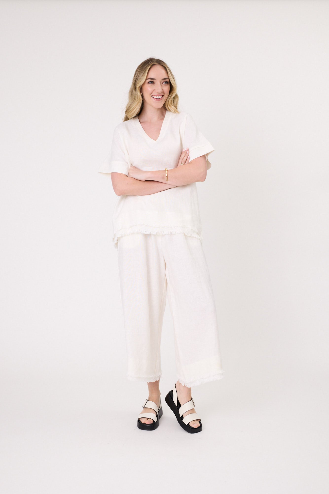 Nicole Linen Pant in white with a loose fit, side pockets, frayed hem, and three-quarter length.