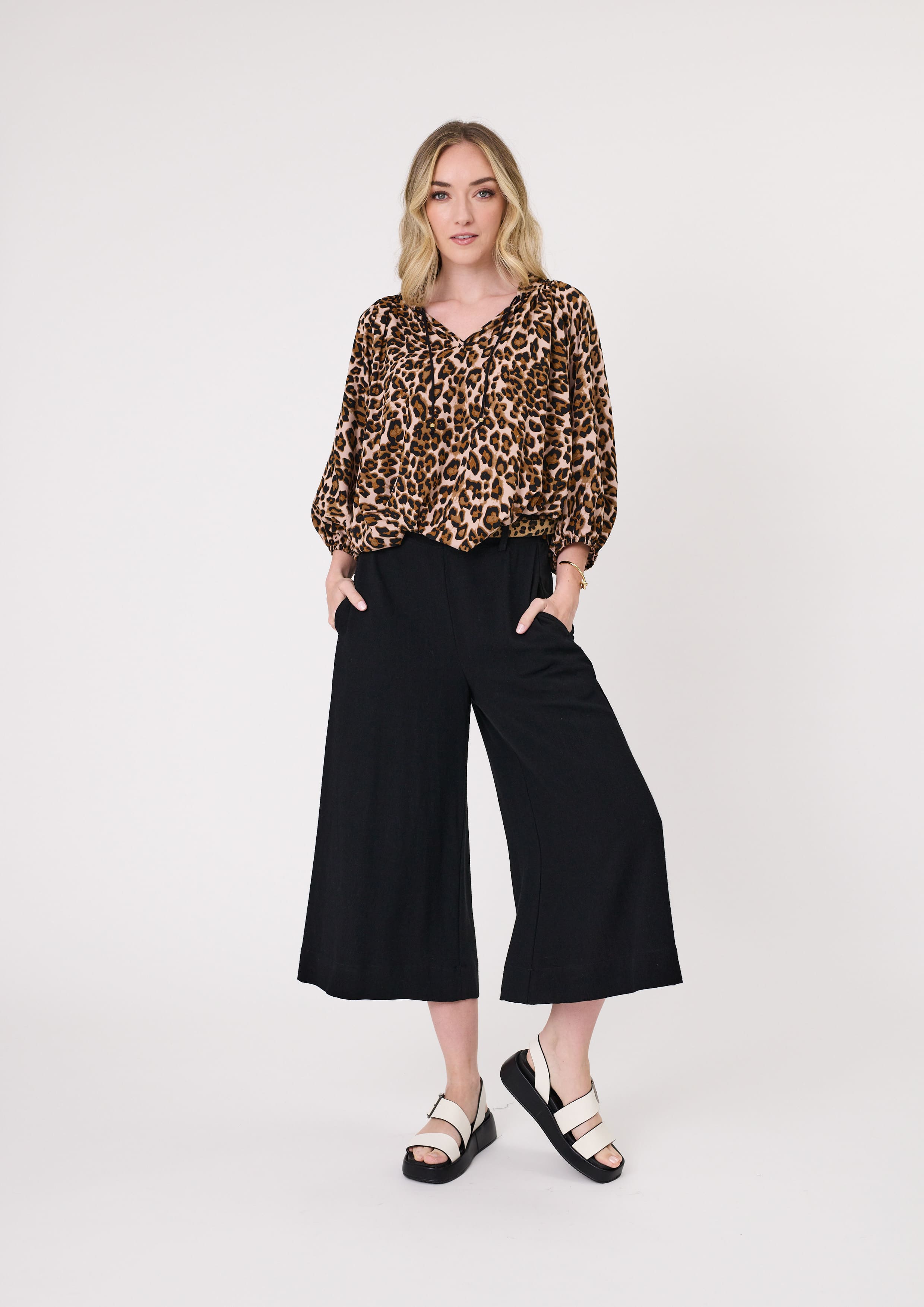 Norma Pant in black with a flowy, wide-leg silhouette, three-quarter length, belt loops, and functional pockets, offering a polished yet relaxed look.